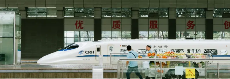 Chinese high-speed train at Yichang station with passengers and vendors.